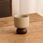 Steingut-Kaffeetasse in Beige mit dunklem Standfuß, kompakte Form