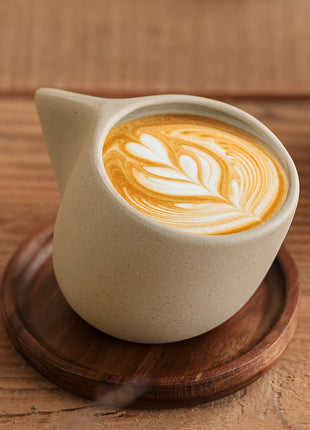Steingut-Kaffeetasse mit Holzuntersetzer, geschwungener Griff, Latte-Art im Inneren