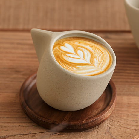 Steingut-Kaffeetasse mit Holzuntersetzer, geschwungener Griff, Latte-Art im Inneren