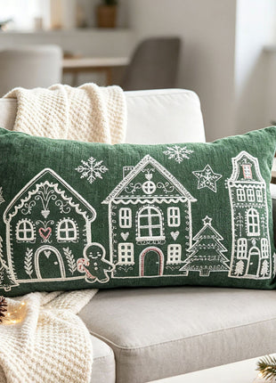 Deep green lumbar Christmas village pillow styled on a sofa