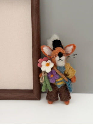 Flower fox wool felt charm beside a wooden frame