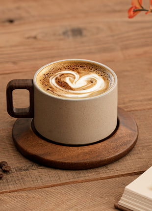 Keramik-Tasse mit Untertasse, beiger Becher mit braunem Griff und Kaffee-Schaumwirbel
