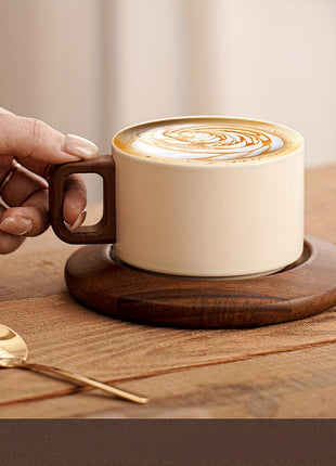 Cremefarbene Keramiktasse auf Untertasse mit Latte-Art, Hand am braunen Holzgriff