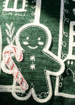 Close-up of gingerbread embroidery on a green Christmas pillow cover