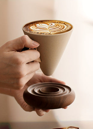 Trichterförmige Keramiktasse mit Kaffee und Spiralsockel aus Holz