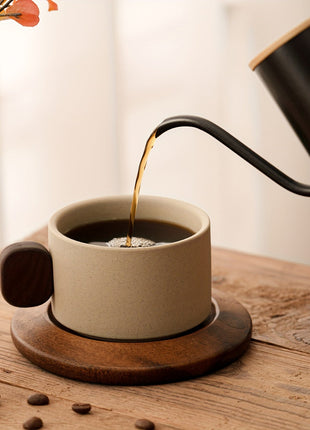 Keramik-Tasse mit Untertasse, beiger Becher mit braunen Griffen, Kaffee wird eingegossen