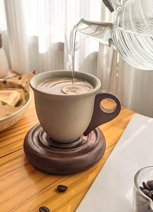 Kaffeetasse mit Holzuntersetzer, Kaffee wird eingegossen, beige Tasse mit Henkel