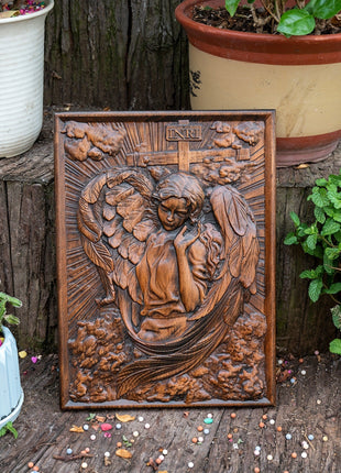Quadratische Holztafel mit geschnitztem Engelmotiv, Relief mit Flügeln und Kreuzdetails.
