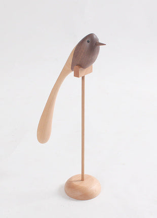Holzvogel-Deko mit langem Schwanz auf rundem Sockel, dunkler Vogel auf Ständer