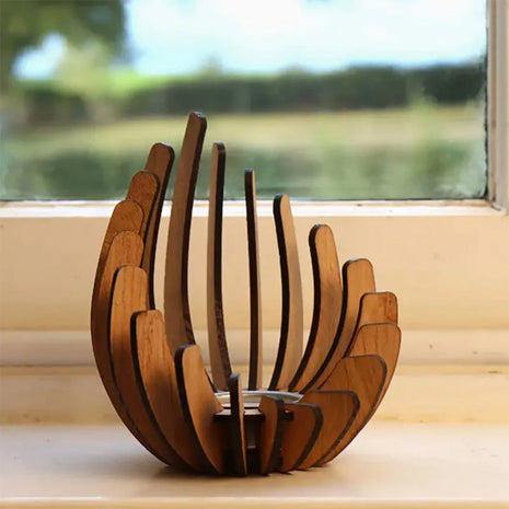 Holz-Kerzenhalter im Lotusdesign mit brennender Kerze am Fensterbrett.
