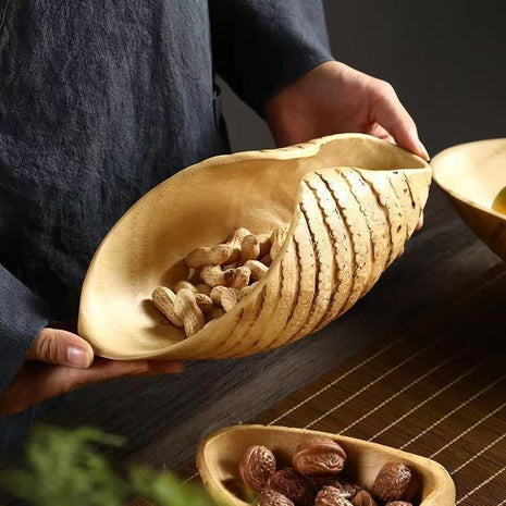 Obstschale aus Bambuswurzel in Bootform, mit Nüssen, von Hand gehalten