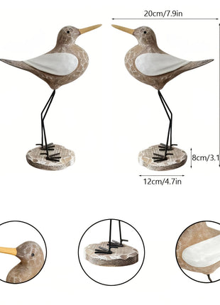 Zwei Holz-Seevögel auf Metallbeinen mit weißem Bauch und gelben Schnäbeln, Sockel