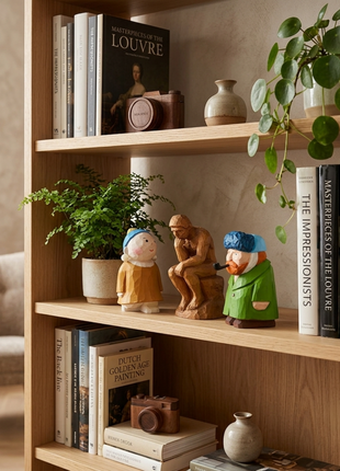 Handgefertigte Holzskulpturen: drei Figuren auf einem Holzregal, mit blauem Kopftuch und grüner Kleidung.
