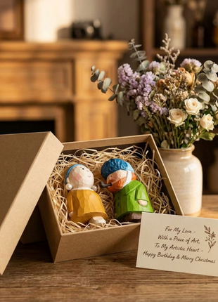 Handgefertigte Holzskulpturen im Geschenkbox-Set: zwei Figuren mit blauem Kopftuch und grünem Mantel.