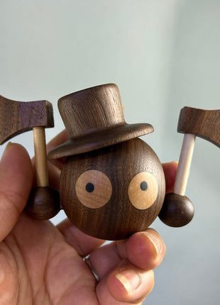 Nahaufnahme: Holz-Kohle-Kugel Figur mit Zylinderhut und großen Knopfaugen