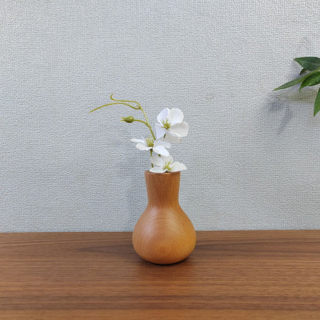 Kleine Holzvase aus Buchenholz mit enger Öffnung und weißer Blüten-Deko auf Tisch