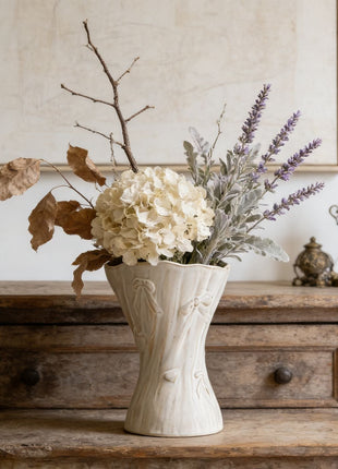 Weiße Keramikvase mit Reliefornamenten und breiter Öffnung, gefüllt mit Blumen
