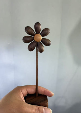 Holzblume aus Holz mit dunklen Blütenblättern und hellem Zentrum auf quadratischem Sockel