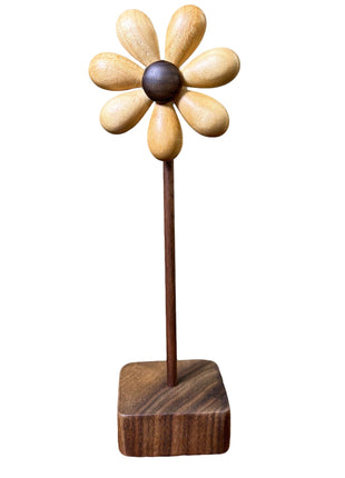 Holzblume aus Holz mit hellen Blütenblättern und dunklem Zentrum auf quadratischem Sockel