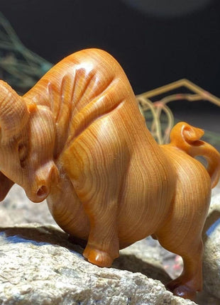Holzfigur eines Stiers aus Thuja-Holz, orangebraun, Rückansicht mit erhobenem Schwanz und Hörnern.