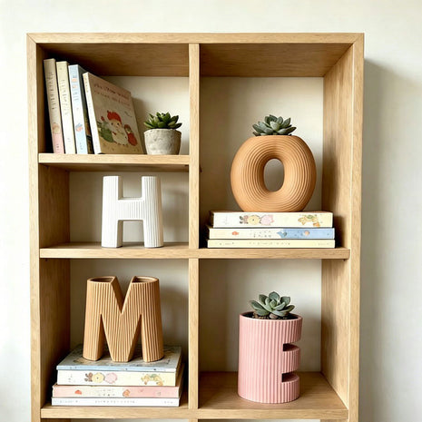 Keramik-Buchstabenvasen-Set im Holzregal: weißes H, orange O, beiges M, rosa Vase