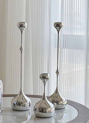 Tropfen-Kerzenhalter-Set aus silbernem Metall mit drei hohen Tropfenfüßen auf dem Tisch