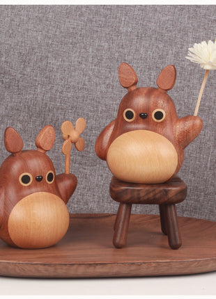 Zwei Totoro-Holzfiguren mit Windrädern, eine auf kleinem Holzständer.