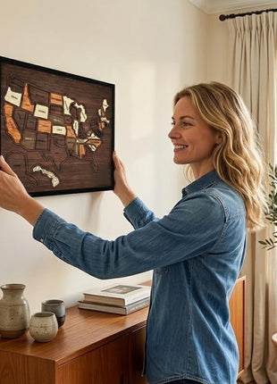 Holz-USA-Kartenpuzzle im Rahmen, Frau hält das Wandbild an der Wand im Wohnraum