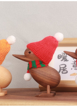 Drei Holzenten mit Strickmützen: orange und rot (mit Pompons) auf Holzsockeln