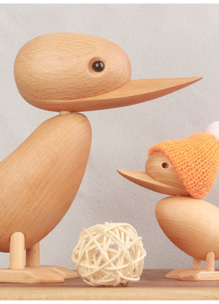 Holzente in hellem Holz mit orangefarbener Strickmütze und kleiner Ente auf Ständer