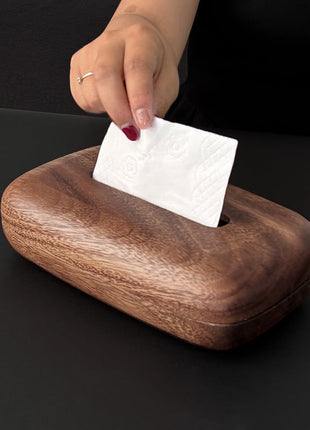 Walnussholz-Taschentuchbox mit Schlitz; Hand legt weißes Taschentuch ein.