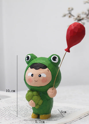 Handgeschnitzte Holzfigur: grüner Frosch-Mensch mit rotem Luftballon und Stock