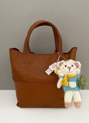 Reading sheep wool felt charm hanging from a brown tote bag