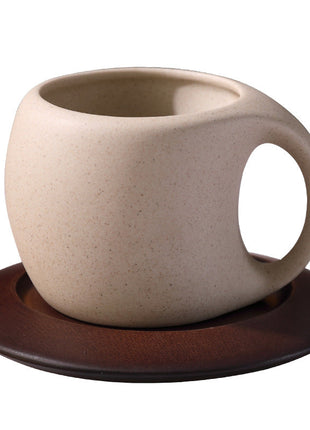 Hellbeige Steingut-Kaffeetasse mit braunem Holzuntersetzer, freigestellt