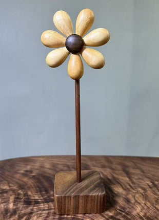 Holzblume aus Holz mit hellen Blütenblättern und dunklem Zentrum auf quadratischem Sockel