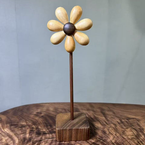 Holzblume aus Holz mit hellen Blütenblättern und dunklem Zentrum auf quadratischem Sockel