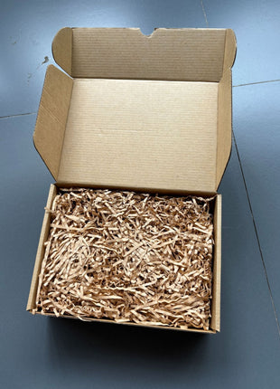Karton mit Füllmaterial und verpackten Holzteilen der Affen-Holzskulptur