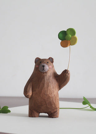 Braune Holzfigur als Bär mit freundlichem Gesicht und grünem Kleeblatt-Ballon