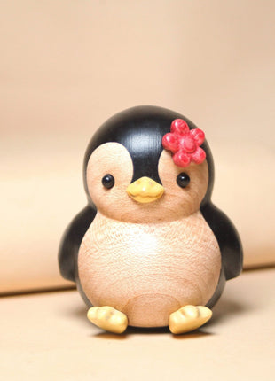 Bemalte Holzfigur: Pinguin mit roter Blume, freundliches Gesicht und gelbe Füße