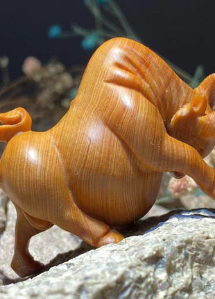 Holzfigur eines Stiers aus Thuja-Holz, orangebraun, Kopf gedreht, Hörner nach vorn, markante Maserung.