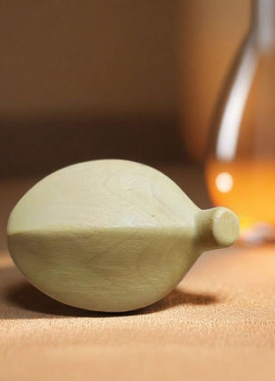 Bananenförmige Holzfigur, hellgelb, seitlich liegend auf Tisch mit kleinem Stiel