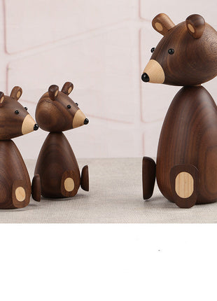 Holzbär-Figuren aus dunklem Holz: ein großer Bär und drei kleinere in Reihe