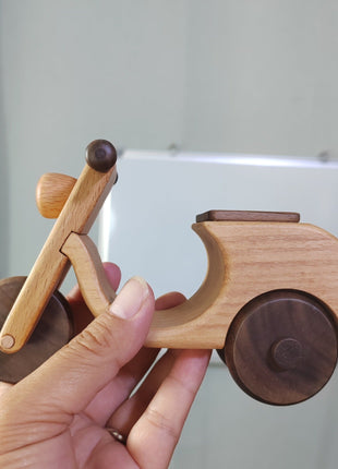 Retro-Motorrad aus Holz, in der Hand gehalten, mit dunklem Rad und sichtbarer Maserung