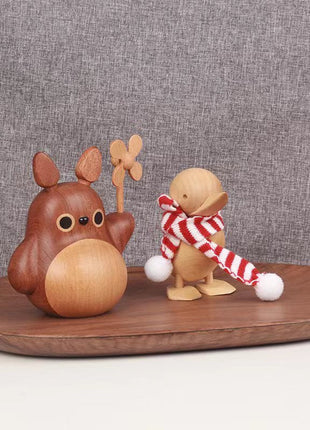 Holzfigur mit Windrad auf Teller-Tablett, neben kleiner Kuscheltier-Figur.