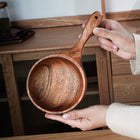 Schöpfkelle aus braunem Holz, Handgriff und runde Schale in Nahansicht