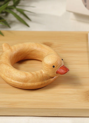 Enten-Holzskulptur im Schwimmring aus hellem Sandelholz, roter Schnabel, auf Holzfläche