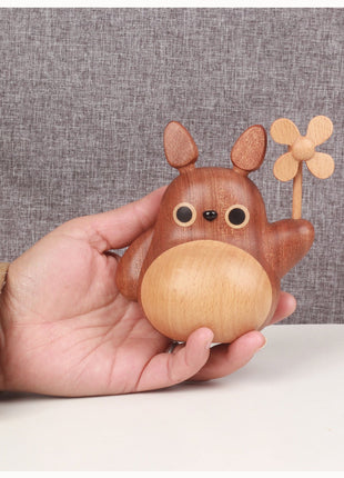 Hand hält Totoro-Holzfigur mit Windrad und rundem Holzgesicht.