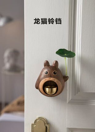 Holz-Türglocke in Totoro-Form am Tür, mit goldenem Klangbecher und grünem Blatthänger