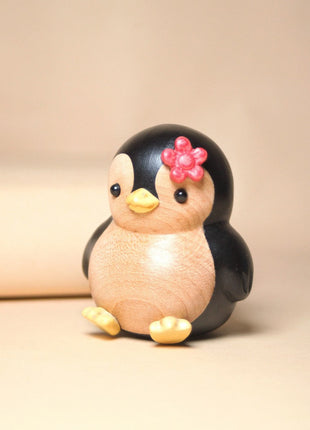 Bemalte Holzfigur: Pinguin mit roter Blume, gedrehte Pose mit gelben Füßen