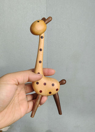 Giraffenfigur aus Holz mit braunen Punkten, in der Hand gehalten